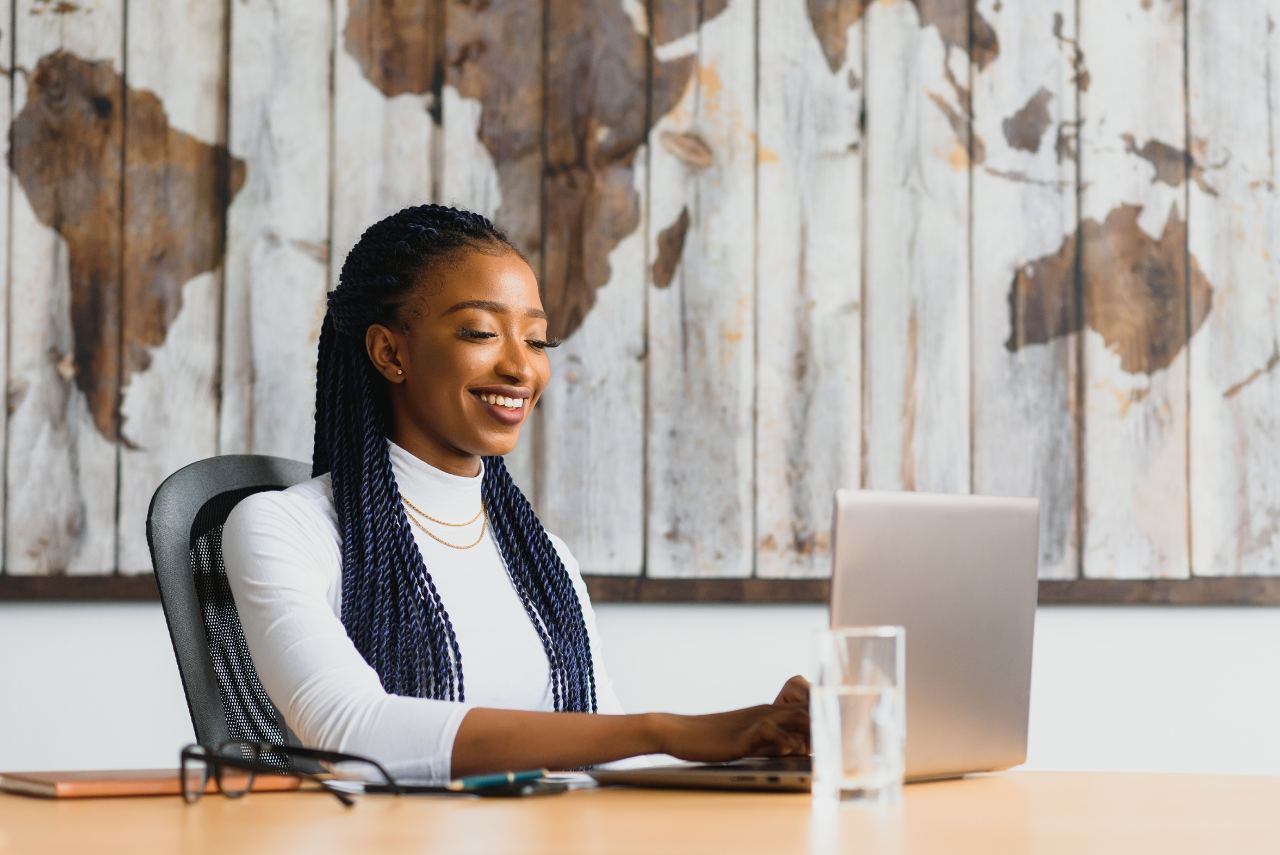 Une professionnelle souriante travaille sur son ordinateur portable à son bureau.